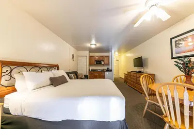 a bedroom with a large white bed and a kitchen at 226 Bldg B condo in Truckee