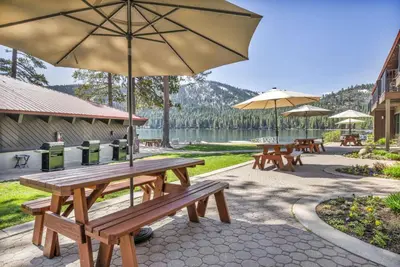 a group of picnic tables with umbrellas and a lake at 111 Bldg B condo in Truckee