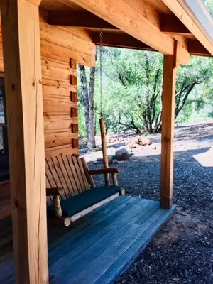 a wooden porch with a swing on a cabin at Apple Valley Cabin in Sonora