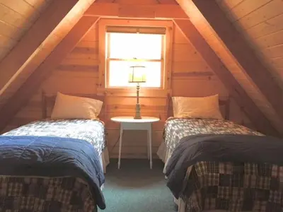 two beds in a attic room with a window at Apple Valley Cabin in Sonora