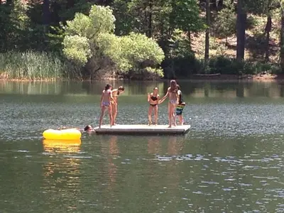a group of people standing on a raft in a lake at Cozy Cabin - Hot Tub, Fire Pit, & Pets in Arnold