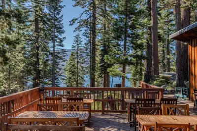 a deck with tables and chairs and trees at Kit Carson Lodge in Kit Carson