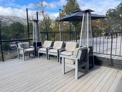 a group of chairs and an umbrella on a deck at Kaweah River Cabin - Pool, Hot Tub, Movie Projector in Three Rivers