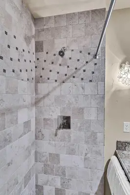 a bathroom with a shower with a stone wall at Star Haven Game Room & Forest Views in Truckee