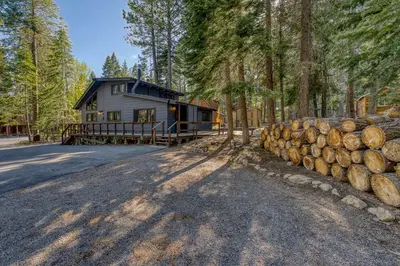 a cabin in the woods with a pile of logs at Laid-Back Tahoe Stay Walk to Lake & EV Charger in Homewood