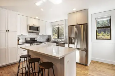 a kitchen with white cabinets and a island with bar stools at Northstar 2BR Walk to Village Bike Hike Rec Center in Truckee