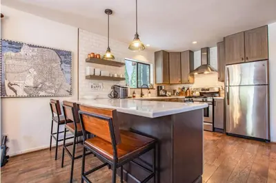 a kitchen with a bar with chairs and a refrigerator at A-Frame Cabin - Hot Tub , BBQ , Family Fun in Tahoe Vista
