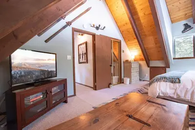 a bedroom with a bed and a flat screen tv at A-Frame Cabin - Hot Tub , BBQ , Family Fun in Tahoe Vista