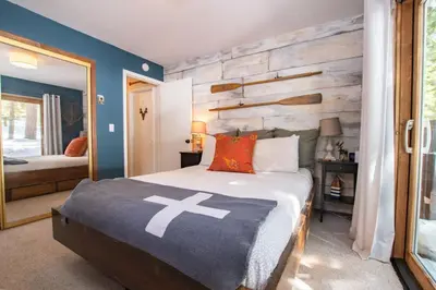 a bedroom with a bed and a wooden wall at A-Frame Cabin - Hot Tub , BBQ , Family Fun in Tahoe Vista