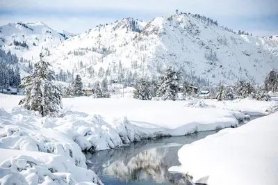 a river covered in snow with mountains in the background at Walk to Palisades Village Pet Friendly 2BR Chalet in Olympic Valley