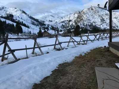 a fence in the snow with mountains in the background at Serene Condo by Palisades Base and Golf Course in Olympic Valley