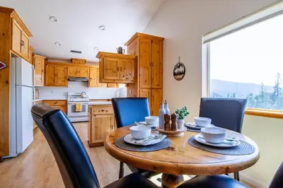a kitchen with a wooden table with chairs and a dining room at Riverfront Serenity with Stunning Views in Mariposa