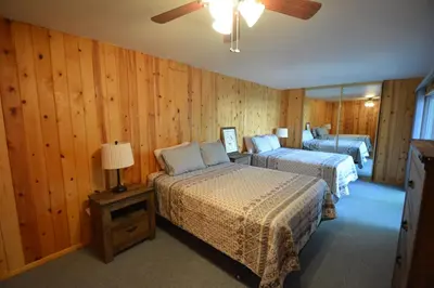 two beds in a room with wood paneled walls at Cozy Cabin with Boat Slip Winter SpecialEnds512 in Bass Lake