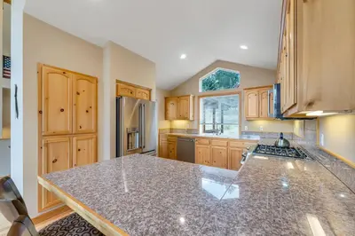 a kitchen with a granite counter top and wooden cabinets at Chestnut Haus at Tahoe Donner By Tahoe Getaways - 4 BR w HOA Amenities in Truckee