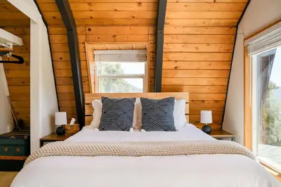 a bedroom with a large bed with wooden walls at Modern A Frame,20min Yosemite,Sunset View, PetOkay in Oakhurst