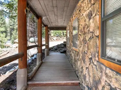 a wooden walkway leading to a building with a stone wall at Yosemite Log Cabin-Rustic Charm-Sleeps 8 in Yosemite West