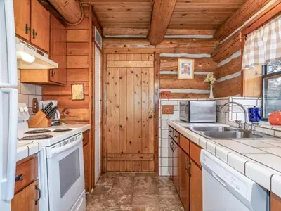 a kitchen with white appliances and wooden walls at Yosemite Log Cabin-Rustic Charm-Sleeps 8 in Yosemite West