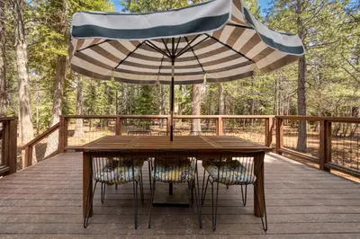 a wooden table with an umbrella on a deck at Charmed Cabin at Tahoe Donner by Tahoe Getaways - 2BR w HOA Access in Truckee