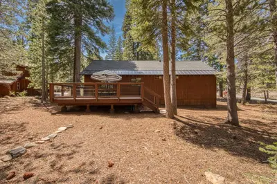 a large wooden cabin in the middle of a forest at Charmed Cabin at Tahoe Donner by Tahoe Getaways - 2BR w HOA Access in Truckee