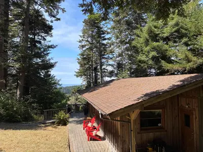 a log cabin with red chairs outside of it at Redwoods Oceanview Retreat