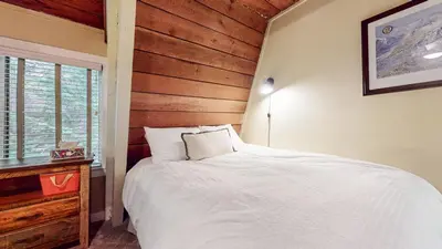 a bedroom with a white bed and a wooden wall at Bigwood #30 condo in Mammoth Lakes
