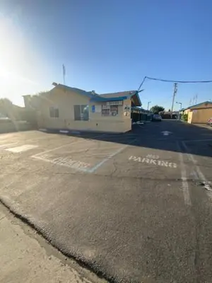 an empty parking lot with a building in the background at Hotel Paisano in Reedley