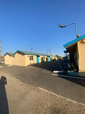 an empty parking lot next to a row of buildings at Hotel Paisano in Reedley