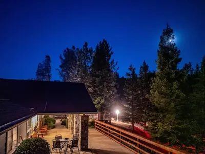 a building with a table and chairs at night at Scenic Mountain Views w Heated Pool, Game Room, and Hottubs in Oakhurst