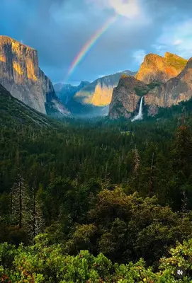 a rainbow over a valley with trees and mountains at Yosemite family getaway w lake, golf, horses, pool in Groveland