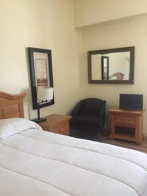 a bedroom with a bed and a chair and a mirror at Whitney Portal Hotel And Hostel in Lone Pine