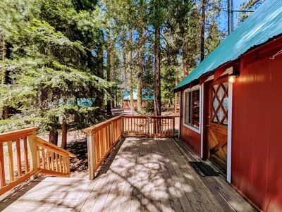 a wooden deck next to a red cabin in the woods at Meadow View Cabin in Wilsonia in Wilsonia
