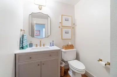 a bathroom with a sink and a toilet and a mirror at The Deco Retreat - UNR - Pet Friendly in Reno