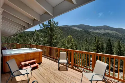 a deck with a hot tub and chairs on it at Tudor Lodge home in Stateline