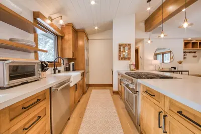 a kitchen with wooden cabinets and a stove top oven at Splendid at Chamberlands by Tahoe Getaways - Chamberlands HOA, Private Hot Tub & Walk to Lake Tahoe in Tahoma