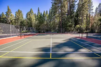 a tennis court with trees in the background at Splendid at Chamberlands by Tahoe Getaways - Chamberlands HOA, Private Hot Tub & Walk to Lake Tahoe in Tahoma