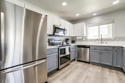 a kitchen with white cabinets and a stainless steel refrigerator at 3 Mi to Dtwn Gated Condo with Patio in Reno! in Reno
