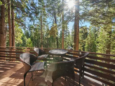 a table and chairs on a deck with trees at Mountain retreat w FirePit, BBQ, Karaoke, PingPong in Arnold