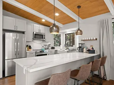 a kitchen with a large white counter and chairs at Mountain retreat w FirePit, BBQ, Karaoke, PingPong in Arnold