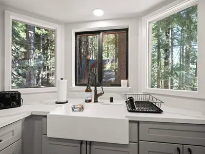 a white kitchen with a sink and two windows at Mountain retreat w FirePit, BBQ, Karaoke, PingPong in Arnold