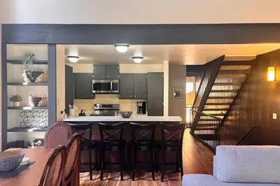 a kitchen with a bar with stools and a staircase at Cozy Bear Retreat in Kings Beach