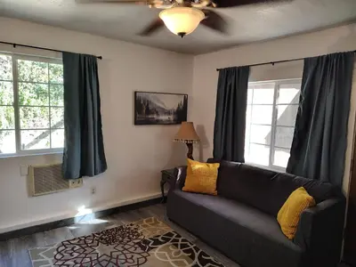 a living room with a couch and two windows at Dew Drop Inn Kings Canyon National Park in Miramonte