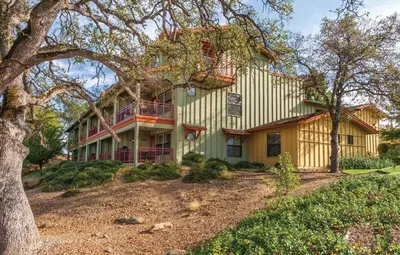a yellow house with a tree in front of it at Wyndham Angels Camp 1BR Apartment with Resort Access in Angels Camp
