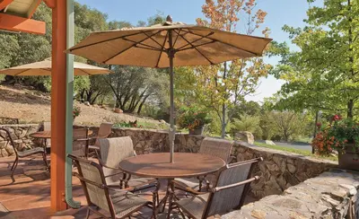 a table and chairs with an umbrella on a patio at Wyndham Angels Camp 1BR Apartment with Resort Access in Angels Camp