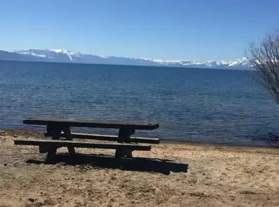 a picnic table sitting on the shore of a lake at #9 Lakeside Location Beach Access View BalconyDog in Kings Beach