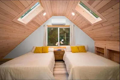 two beds in a attic room with a window at Stay At 4K in Arnold