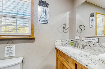 a bathroom with a sink and a mirror and a toilet at Little Cozy Cabin in Shaver Lake