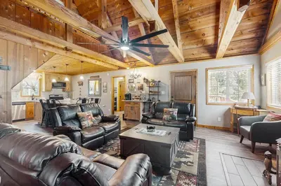 a living room with leather furniture and a wooden ceiling at Little Cozy Cabin in Shaver Lake