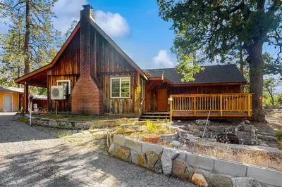 a wooden house with a porch and a yard at Little Cozy Cabin in Shaver Lake