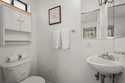 a white bathroom with a toilet and a sink at Tahoe Peaks & Shores Getaway in Kings Beach