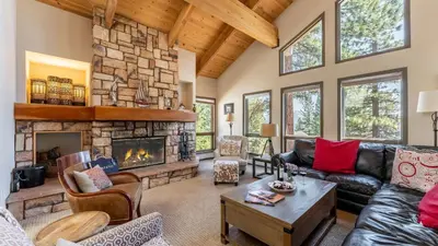 a living room with a large stone fireplace at Crystal View by AvantStay Al Fresco Dining w View of Lake Tahoe Crystal Bay in Incline Village